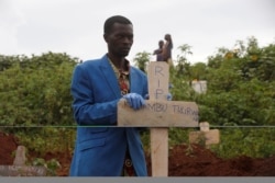 FILE - A Congolese man holds a cross during the burial service of Congolese woman who died of Ebola, at a cemetery in Butembo.