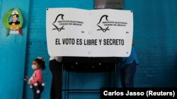 Seorang anak sedang menunggu orang tuanya melaksanakan hak pilih dalam pemilihan umum di Mexico City, Meksiko, Minggu, 6 Juni 2021.