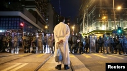 在香港坚尼地城，一名宗教人士站在防暴警察前。(2019年8月4日)