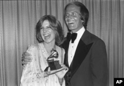FILE - Debby Boone holds her Grammy award for best new artist as she gets a hug from her father, singer Pat Boone, at the Grammy Awards in Los Angeles, Feb. 21, 1978.