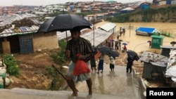 Rohingya refugees walks along the refugee camp during rain in Cox’s Bazar, Bangladesh, July 25, 2018.