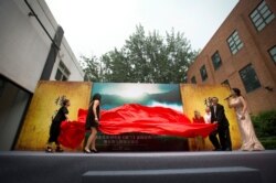 Movie executives, including Hollywood director Catherine Hardwicke, fourth from right, pull a sheet away from a poster promoting Hardwicke's upcoming movie "Loulan" during a press conference in Beijing.