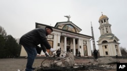 FILE - A man clears rubble in front of St. Andrew's Cathedral, which was damaged by a Russian strike on Zaporizhzhia, Ukraine, Jan. 18, 2025.