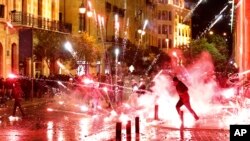Anti-government protesters throw firecrackers at riot police during a demonstration against the new government, near Parliament Square, in Beirut, Lebanon, early Wednesday, Jan. 22, 2020. 