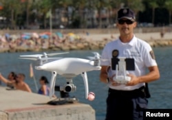 Local police officer Agustin Mirete controls a drone equipped with a camera used for surveillance tasks in the Poniente beach at the eastern costal town of Benidorm, Spain, Aug. 18, 2016.