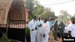 FILE - Health officials stand outside La Terrasse restaurant in Bamako, where five people were killed in a militant attack, March 7, 2015. 