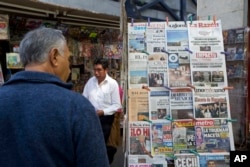 A man stops to read headlines, many featuring U.S. President Donald Trump's actions to jumpstart construction on a promised border wall and his insistence that Mexico will foot the bill, in Mexico City, Jan. 26, 2017.