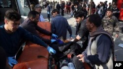 An injured man is moved to a stretcher outside a hospital following a suicide attack in Kabul, Afghanistan, Jan. 27, 2018.