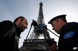 A French police officer talks to French Prime Minister Edouard Philippe during his visit to mark the end of a two-year state of emergency imposed in France, Wednesday, Nov. 1, 2017 near the Eiffel Tower in Paris. Philippe says the deadly truck attack on a New York bike path is a reminder that the threat is high everywhere, and that authorities must remain "as humble as we are determined" to fight extremism.