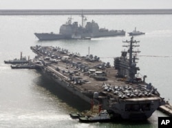 FILE - U.S. aircraft carrier USS Ronald Reagan anchors as U.S. Aegis Ship passes after they arrive at Busan port for joint military exercises in Busan, South Korea. The United States and South Korea started joint naval exercises, Nov. 11, 2017.