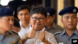 Reuters journalist Wa Lone, center, gives a thumbs up sign as he is escorted by police upon arrival at the court for trial in Yangon, Myanmar Friday, April 20, 2018. 