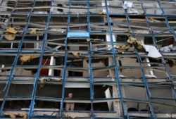 A man looks through a broken window of a building that was damaged by the Aug. 4 explosion that hit the seaport of Beirut, Lebanon, Aug. 25, 2020.
