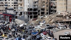 People gather as vehicles drive near damaged buildings, in Beirut's southern suburbs, after a ceasefire between Israel and Hezbollah took effect, Lebanon, Nov. 27, 2024. 