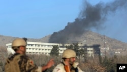 Afghan security personnel stand guard as black smoke rises from the Intercontinental Hotel, Jan. 21, 2018, after an attack in Kabul, Afghanistan. Gunmen stormed the hotel and set off a 12-hour gun battle with security forces that continued into Sunday morning, as frantic guests tried to escape from fourth- and fifth-floor windows.