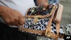 Government worker slashes counterfeit Louis Vuitton handbag during ceremonial destruction of fakes goods seized in raids, Manila, Philippines, June 30, 2011.