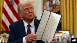 প্রেসিডেন্ট ট্রাম্প ২০২৫ সালের ২৩ জানুয়ারি ওয়াশিংটনে হোয়াইট হাউসের ওভাল অফিসে স্বাক্ষরিত একটি দলিল তুলে ধরেন।