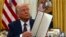 Претседателот Доналд Трамп држи потпишана извршна наредба во Овалната канцеларија во Белата куќа, во Вашингтон, 23 јануари 2025 година