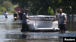 People use an air mattress to float possessions out of a flooded area of Port Arthur, Texas, Aug. 31, 2017. Health officials warn people to avoid floodwaters, which could be contaminated, electrified or hiding sharp objects.