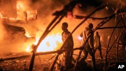 FILE - People walk by U.N. vehicles which were set on fire, in Goma, Democratic Republic of Congo, on Nov. 1, 2022.