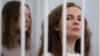 FILE - Belarusian journalists Katsiaryna Andreyeva and Darya Chultsova stand inside a defendants' cage during a court hearing in Minsk, Belarus, Feb. 18, 2021.