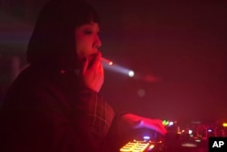 FILE - A DJ who goes by the stage name Kuro smokes a cigarette as she plays music in Changchun in northeastern China's Jilin province on Oct. 12, 2024.