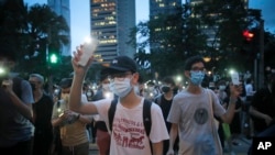 Pro-democracy demonstrators march holding their phones with flashlights on during a protest to mark the first anniversary of a mass rally against the now-withdrawn extradition bill in Hong Kong, June 9, 2020.