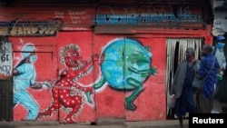 Vendors, carrying traditional medicine in jerrycans, stand outside a stall which has graffiti against the spread of the coronavirus disease (COVID-19) within Kibera slums in Nairobi, Kenya, July 6, 2020. 