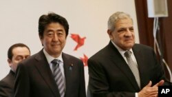 Japanese Prime Minister Shinzo Abe and Egyptian Prime Minister Ibrahim Mahlab arrive at a joint meeting of the Japan-Egypt business committee in Cairo, Egypt, Saturday, Jan. 17, 2015.