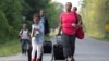 FILE - Members of a Haitian family walk toward the U.S.-Canada border from Champlain, N.Y., Aug. 11, 2017. Haiti has asked the U.S. government to extend TPS status for its nationals. 