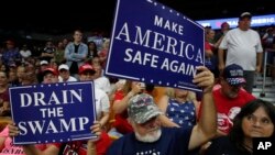Supporters hold signs as President Donald Trump speaks during a rally, Aug. 21, 2018, in Charleston, West Virginia. 