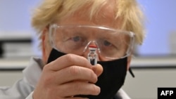Britain's Prime Minister Boris Johnson poses for a photograph with a vial of the AstraZeneca/Oxford University COVID-19 candidate vaccine at Wockhardt's pharmaceutical manufacturing facility in Wrexham, north Wales, on Nov. 30, 2020.