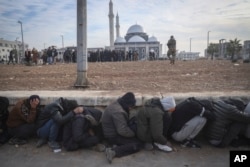 Government soldiers and their allies huddle on the ground while being detained by insurgents in Homs, Syria, Dec. 8, 2024.