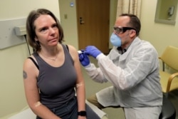 A pharmacist gives Jennifer Haller, left, the first shot in the first-stage safety study clinical trial of a potential vaccine for COVID-19 at the Kaiser Permanente Washington Health Research Institute in Seattle, Washington, March 16, 2020.