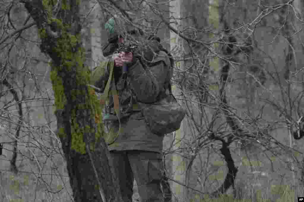 An unidentified gunman aims his assault rifle while he and others block the road toward the military airport at the Black Sea port of Sevastopol in Crimea, Ukraine, Feb. 28, 2014.