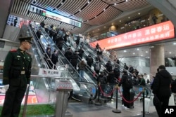 2025年1月18日，北京西站內站崗的武警士兵和準備搭火車回家過春節的返鄉大軍。