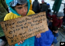 A migrant boy shows a banner saying he wants to travel to Germany rather than camps set up by Turkey, during a protest demanding the opening of the border between Greece and Macedonia in the northern Greek border station of Idomeni, Greece, March 23, 201