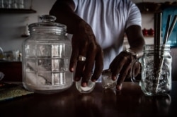 Babacar Thiaw sets up reusable containers containing sugar, salt and pepper and metal straws. Thiaw has spent the last year transitioning his restaurant to a zero waste haven. (A. Hammerschlag/VOA)