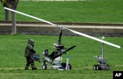 A member of a bomb squad checks a small helicopter after a man landed on the West Lawn of the Capitol, April 15, 2015.