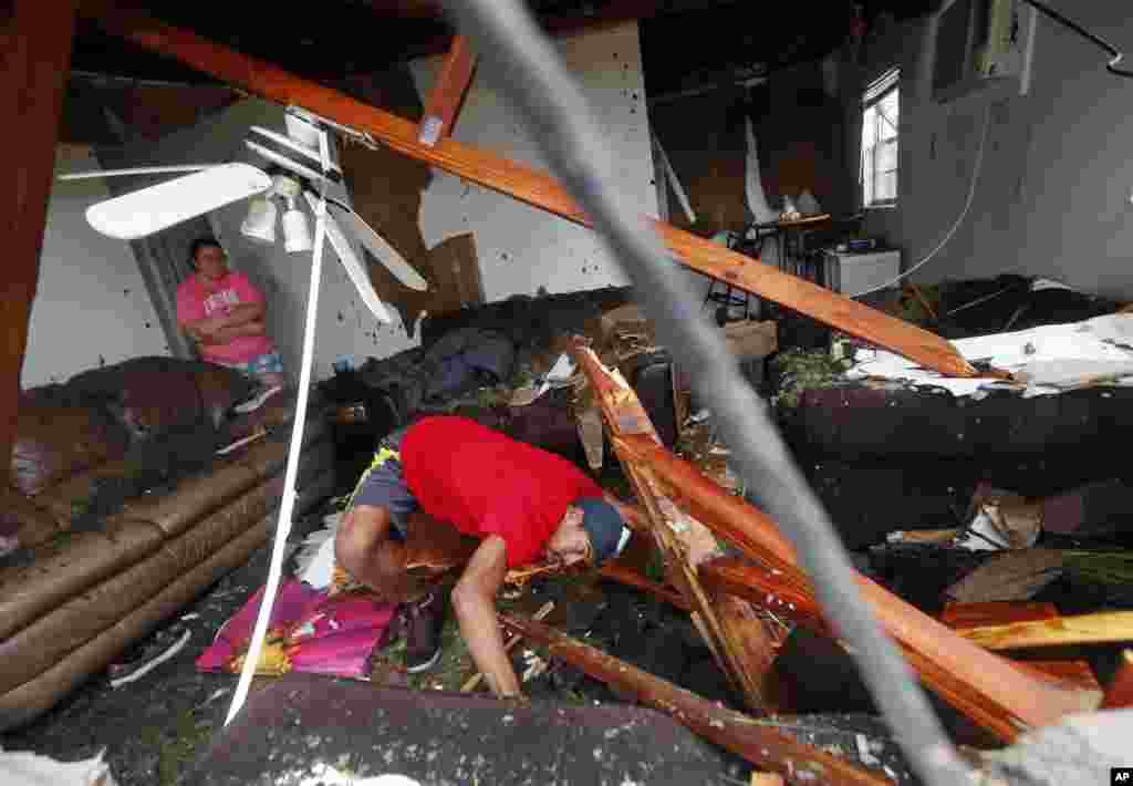 Dorian Carter looks under furniture for a missing cat after several trees fell on their home during Hurricane Michael in Panama City, Fla., Oct. 10, 2018. 