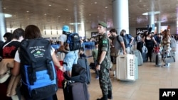 FILE - A Brazilian officer directs Brazilians as they check in to leave Israel, from Ben Gurion International Airport near Tel Aviv on Oct. 14, 2023, amid the ongoing battles between Israel and the Palestinian group Hamas.