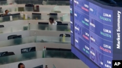 Traders wearing protective masks to prevent the spread of the coronavirus work beside an electronic board showing morning market summaries at the Philippine Stock Exchange in Taguig, Philippines, Nov. 4, 2020.