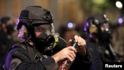 Seorang petugas penegak hukum federal memegang bola merica saat protes menentang ketidaksetaraan rasial dan kekerasan polisi di Portland, Oregon, AS, 28 Juli 2020.