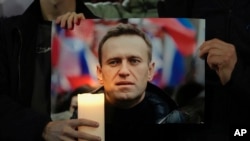 Para pengunjuk rasa memegang foto Alexey Navalny saat melakukan demonstrasi di seberang Kedutaan Besar Rusia di London, Jumat, 16 Februari 2024. (Foto: AP)