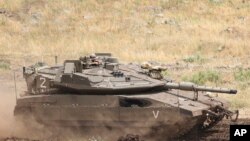 An Israeli tank drives in the Israeli-controlled Golan Heights, near the border with Syria, May 10, 2018. 