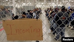 FILE - Undocumented immigrants wait in a holding facility after arriving at the U.S. Border Patrol detention.