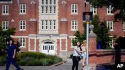 FLE- A University of Connecticut student waits for the traffic light to change outside a dormitory building on the campus in Storrs, Conn., Sept. 18, 2015.