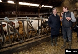 Politician Jean-Luc Melenchon (L), of the French far-left Parti de Gauche, and candidate for the 2017 French presidential election, listens to a farmer during a visit to a farm in Saint-Germain-la-Poterie, France, Feb. 27, 2017.