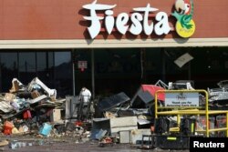 A worker wearing protective clothing helps as the clean-up continues at a neighborhood shopping plaza following the aftermath of tropical storm Harvey in Houston, Texas, Sept. 9, 2017.