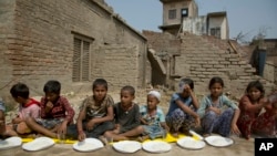 Nepalese children wait for the food to be distributed as they sit next to their houses damaged in a rainstorm in Bara district, 125 kilometers (75 miles) south of Kathmandu, Nepal, April 1, 2019.
