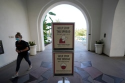 FILE - A woman wears a mask as she walks on campus at San Diego State University, Sept. 2, 2020, in San Diego.